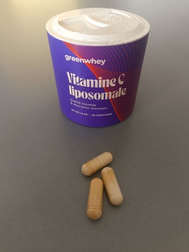 Un client montre le pot de Vitamine C liposomale et trois gélules posées à côté.