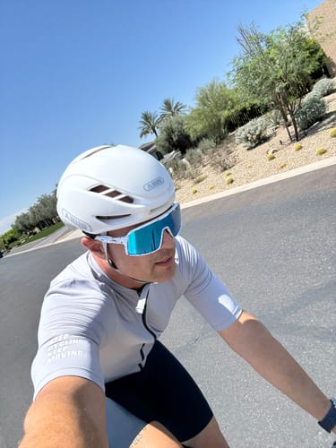 Customer wearing the gray Vividness Jersey while cycling on a sunny road.