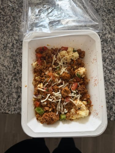 Customer's Morning Scramble in its white container, with the plastic film peeled back to show the prepared meal.