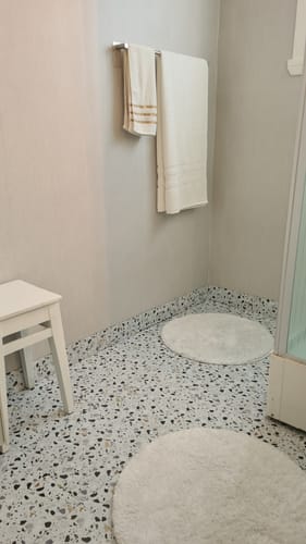 Anmelder viser de ferdiglagte terrazzo-gulvflisene på et baderomsgulv.