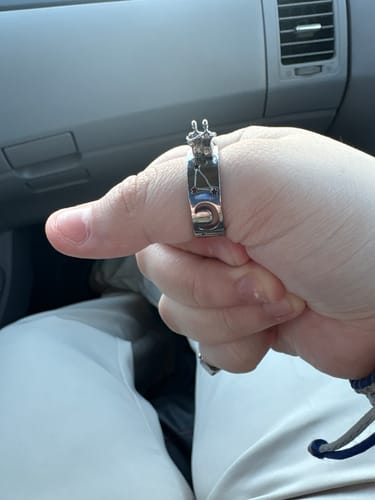 Customer's thumb with the silver Stargazers Ring, showing the two figures and celestial designs.