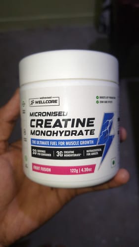 Customer holding a white tub of Wellcore Micronised Creatine Monohydrate, Fruit Fusion flavor.