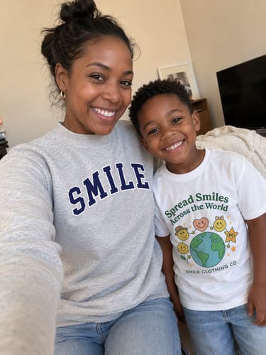Reviewer's child smiling while wearing the white Kids Spread Smiles Across The World Shirt.