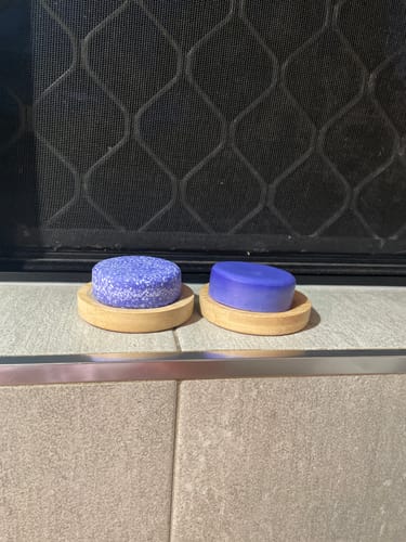 Customer's two Bamboo Bar Holders with a purple shampoo bar and conditioner bar on a tiled shower ledge.