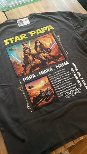 Ein Kunde zeigt die Rückseite seines personalisierten, dunklen 'Star Papa' T-Shirts mit einem großen Familiendruck.