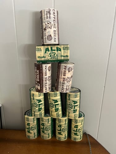 Reviewer's pyramid stack of Coffee Break Caffeine Pouches tins on a wooden table.