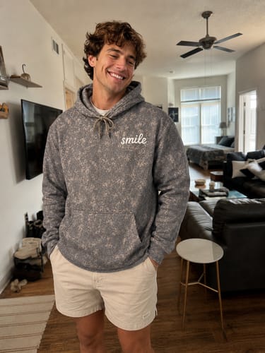 Customer wearing the grey Statement Collection Camo Hoodie, showing its comfortable fit indoors.
