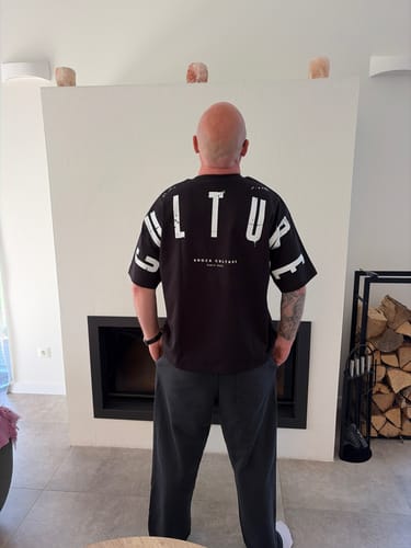 Customer from behind wearing the oversized black CULTURE HEAVY TEE, showing the back print.