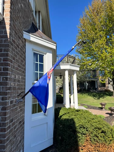 Customer's old style Minnesota flag completely tangled and wrapped around the flagpole next to a door.