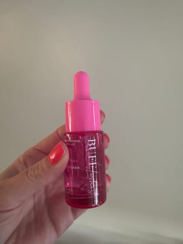 Reviewer holding the small Buff Lashes VitaLash serum bottle, showing its bright pink dropper top.
