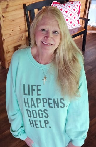 Reviewer smiling while wearing the light green 'Life Happens Dogs Help' sweatshirt.