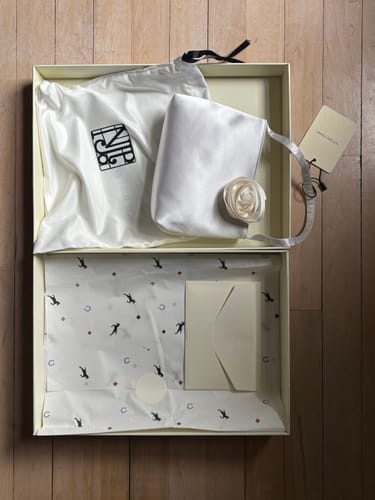 Reviewer's white Tuscan Rose Handcrafted Silk Bag and its dust bag presented inside an open box.