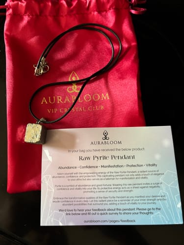 Customer's raw pyrite pendant from the VIP Crystal Club next to its red pouch and info card.