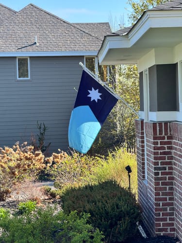 Reviewer's comparison photo showing a neighbor's flag flying freely and untangled from a pole.