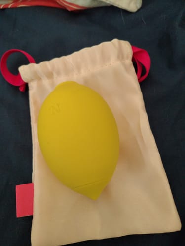 Customer's yellow Lem Clitoral Massager shown resting on top of its white storage pouch.