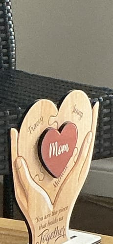 Customer's personalized wooden plaque with hands holding puzzle pieces with names, centered with a red heart that says 'Mom'.