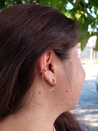 Cliente mostrando cómo luce el Ear Cuff con extensión dorado en la oreja.