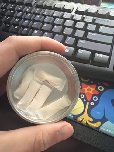 Reviewer holding an open tin of Drifters Blueberry Lemonade Ice Nicotine Pouches, showing several white pouches inside.