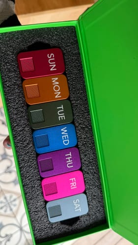 Reviewer's colorful MagNano Case set showing seven daily pill containers inside the open, bright green travel case.