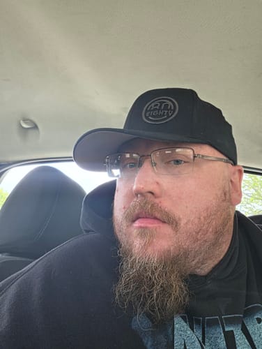 A reviewer wearing the black 80Eighty 3D fitted hat while sitting in a car.