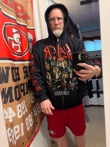 Reviewer wearing the black Slayer 'Reign In Blood' deluxe zipper hoodie with the hood up in a mirror selfie.