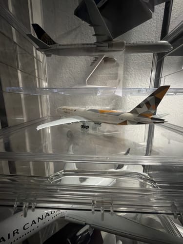 Customer's Etihad Cargo 777-200F model airplane on a clear shelf inside a multi-level display case.