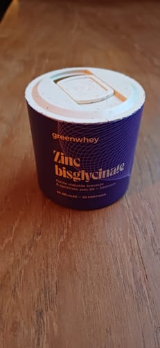 Photo d'un client montrant le pot violet de Zinc Bisglycinate sur une surface en bois.