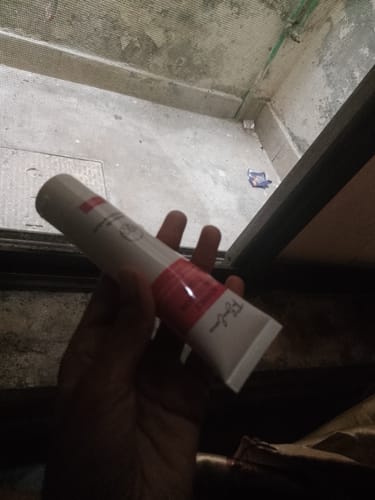 Customer holding a tube of the Pigmentation Correcting Cream in a dimly-lit setting.