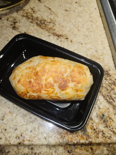 Customer's Bison Kickstart Burrito with a golden-brown tortilla in a black container.