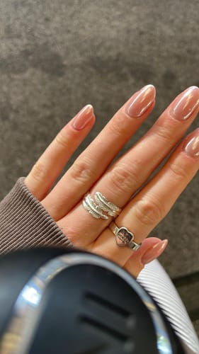 Customer's hand wearing two silver rings, one feather-shaped and one heart-shaped.