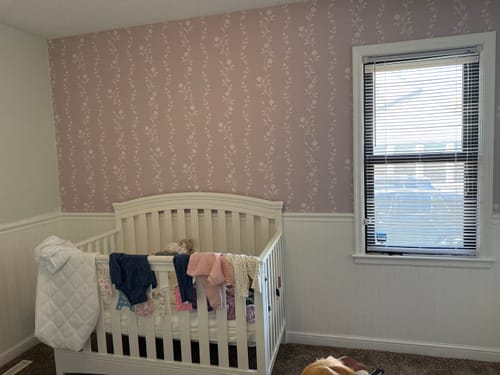 Customer's Rosalee Wallpaper in light purple on a nursery wall above a white crib.