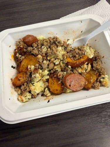 Customer's Beast Mode Breakfast with turkey, sausage, and potatoes over eggs in a white container.