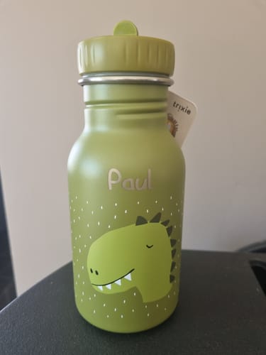 Kunde zeigt die grüne personalisierte Trixie Edelstahl-Trinkflasche mit Dino-Motiv und dem Namen 'Paul'.