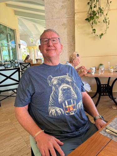 Reviewer sitting at a table wearing the blue Whiskey Dog Cane Corso Paws T-Shirt.