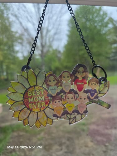 Customer's personalized sunflower suncatcher with 'Best Mom Ever' and family illustrations hanging in a window.