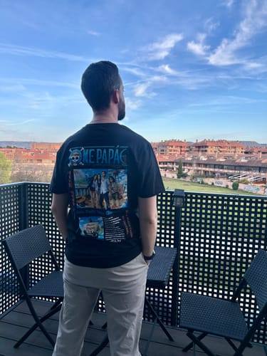 Kunde von hinten, der das personalisierbare 'One Papá'-T-Shirt auf einem Balkon trägt.