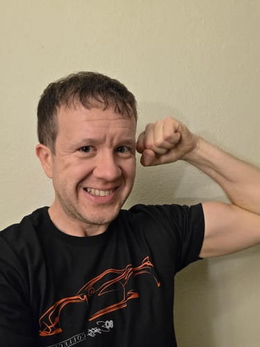 Customer smiling and flexing in a black Rosso Silhouette Shirt, showing how it fits.