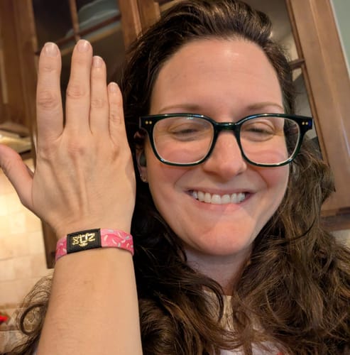 Reviewer smiling while showing the pink Happy Birthday Bracelet on her wrist.