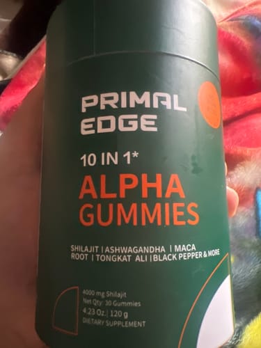 Customer holding the dark green container of PrimalEdge 10-in-1 Alpha Gummies.