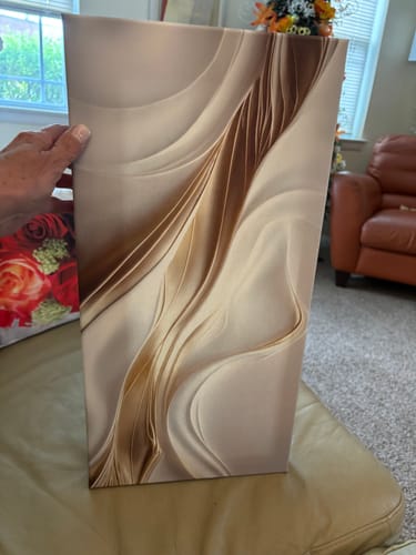 Reviewer holding the vertical Earthtone Petals canvas in their living room.