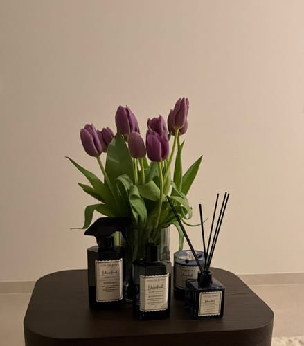 Recensent toont producten uit de Istanbul Bosphorus-lijn, waaronder de Eau de Cologne, op een tafel met tulpen.