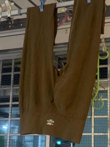 Customer's brown 3D Anti-Cellulite Leggings hanging to dry on a clothing rack indoors.
