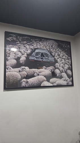 Customer's Black Oak Gallery Frame hanging on a wall, displaying a large print of a car and sheep.