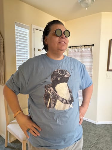 Customer wearing the light blue Dream Beyond Limitations T-Shirt with a large penguin graphic.