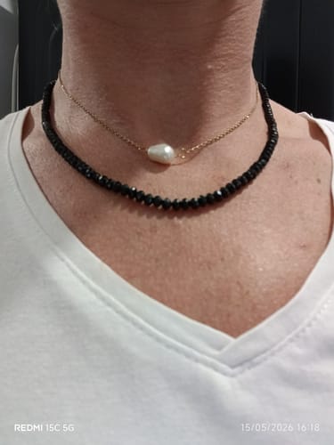 Une cliente porte le Collier en Spinelle Noir superposé avec un collier de perles.