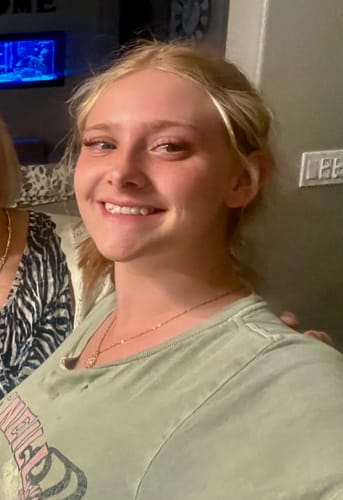Customer's granddaughter smiling while wearing her sparkly You Are My Sunshine Necklace.