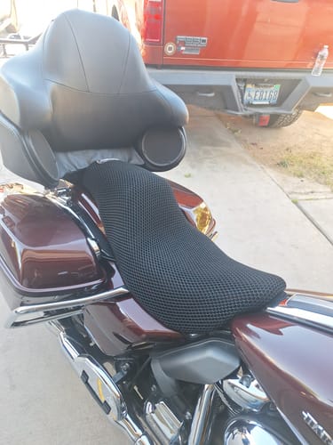 Customer's side view of the black Wind Rider Seat Cover fitted onto the seat of a dark red motorcycle.