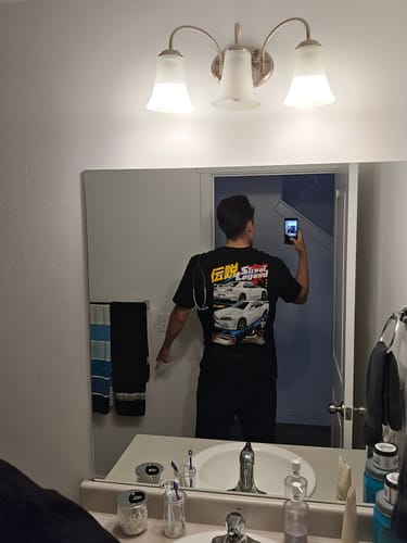Reviewer taking a mirror selfie, showing the back graphic of the black STREET LEGEND TEE.