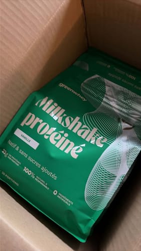 Un client montre le sachet vert de Milkshake protéiné vanille à l'intérieur d'un colis.