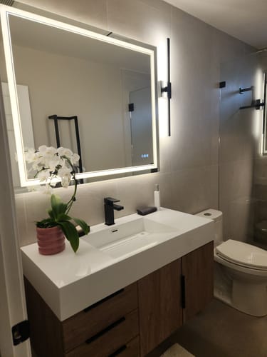 Customer's Breton Floating Vanity with a wood-grain cabinet and white sink, installed in a modern bathroom with a backlit mirror.